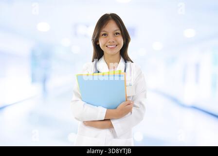 Souveräner südostasiatischer Medizinstudent. Junge Ärztin, die auf Krankenhaushintergrund steht Stockfoto