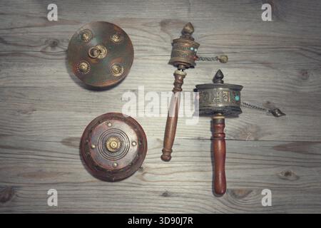 Tibetisches Gebetsrad oder Mani-Rad auf altem hölzernem Hintergrund, dramatisches Licht in Vintage-Ton Stockfoto