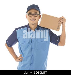 Lieferperson, die das Paket lächelnd in blauer Uniform ausliefert. Schöner junger asiatischer Mann professioneller Kurier isoliert auf weißem Hintergrund Stockfoto