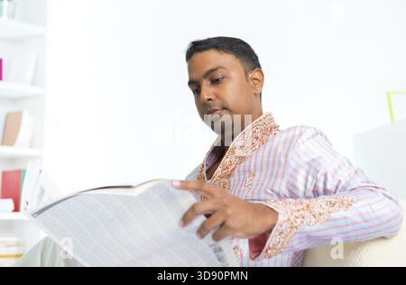 Mittleres Alter der 30er Jahre indische männlich lesen Zeitung zu Hause auf sofa Stockfoto