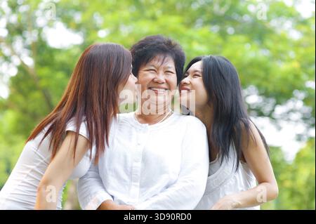 Junge asiatische Tochter küssen ihre senior Mutter, Outdoor-park Stockfoto