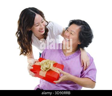 Glückliche asiatische Mutter mit gemischter Rasse, die von ihrer Tochter geschenkt wird Stockfoto