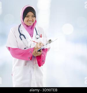 Südostasiatischer muslimischer Medizinstudent. Junge Ärztin, die auf Krankenhaushintergrund steht Stockfoto