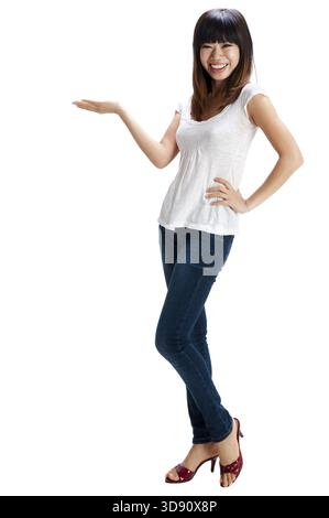 Die ganze Länge einer fröhlichen, fröhlichen, jungen asiatischen Frau, die ihre Hand aushält und den Kopierraum für Ihr Produkt zeigt Stockfoto