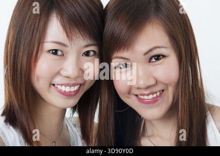 Schließen Sie sich fröhlich asiatische Mädchen auf weißem Hintergrund Stockfoto