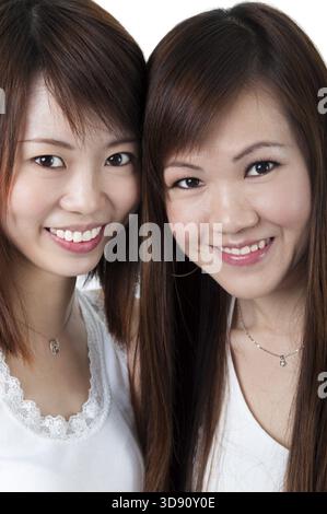 Schließen Sie sich fröhlich asiatische Mädchen auf weißem Hintergrund Stockfoto