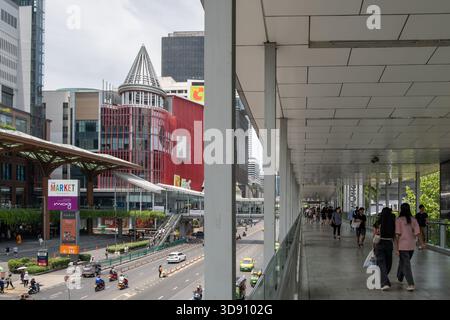 Bangkok, Thailand - 28. Juni 2024: Eine Straßenszene in Bangkok zeigt Fußgänger, die auf einem belebten Bürgersteig mit moderner Architektur und Geschäften spazieren Stockfoto