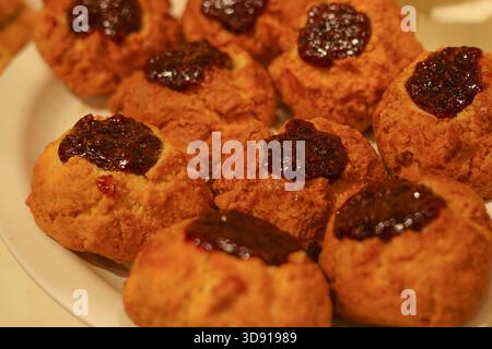 Gebackene Scones mit Berry Marmelade serviert auf einem Teller unter heller Beleuchtung Stockfoto