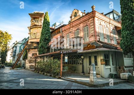 Der schiefe Uhrenturm des Puppentheaters Rezo Gabriadze in Tiflis, Georgien, leuchtet im sanften Morgenlicht. Schrullige Architektur und pastellfarbene faca Stockfoto