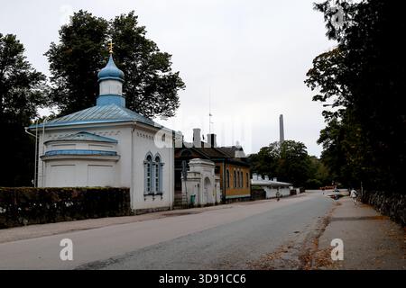 Kleine weiße Kapelle mit blauer Kuppel und Kreuz steht neben gelbem Holzhaus und langem weißen Nebengebäude in einer ruhigen Straße im städtischen Helsinki, Finnland. Stockfoto