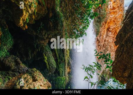 Vertikaler Blick auf den mächtigen Wasserfall, moosbedeckte Klippen und Orange Rocks im Deep Natural Canyon, Monasterio de Piedra Stockfoto