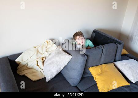 Ein Kind umarmen seinen kleinen Hund, während es sich auf einer bequemen Couch zu Hause ausruht und einen friedlichen Moment zusammen genießt Stockfoto