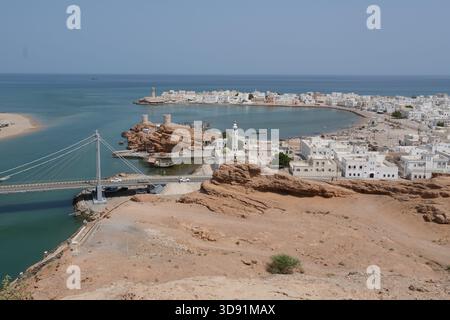 Küstenstadt Sur im Oman mit Hängebrücke, weißen Gebäuden und felsiger Halbinsel Stockfoto