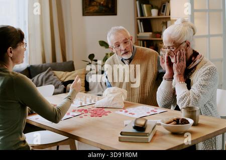 Ältere Frau reagiert beim Brettspiel mit Seniorenpaar Stockfoto