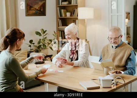 Ältere Frau und Mann spielen Karten mit jungen Erwachsenen Stockfoto