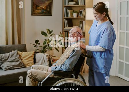 Seniorenmann mit Behinderung, der im Rollstuhl sitzt und unterstützt wird Stockfoto