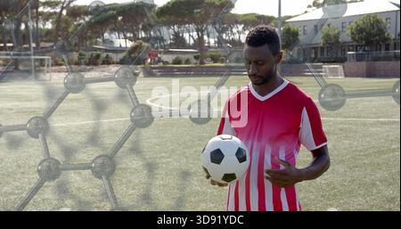 Ein Mann, der Fußball auf markiertem Rasen hält, aus rot-weißem Jersey, Sechskant-Überzug, Kopierraum Stockfoto