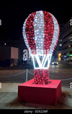 Riesige rote und weiße Heißluftballondekoration, beleuchtet nachts während der Weihnachtszeit. Stockfoto