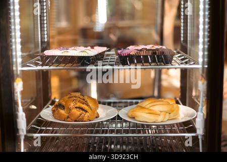 Nahaufnahme von verschiedenen gebackenen Backwaren hinter einer Glasvitrine – frische Croissants, Gebäck und süße Brötchen. Perfekt für Bäckerei, Essen, Lifestyle Stockfoto