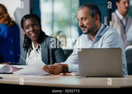 Lächelnde schwarze Frau leitet Feedback-Sitzung im modernen Open Office Stockfoto