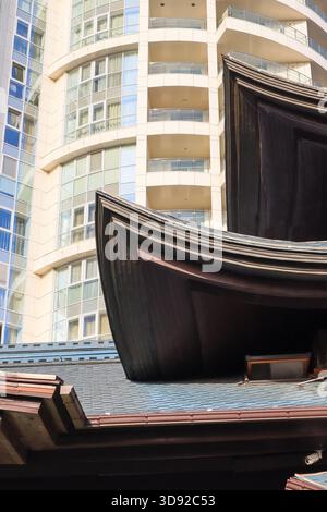 Modernes städtisches Hochhaus mit charakteristischem geschwungenem Dachüberhang und reflektierenden Glasfenstern an sonnigen Tagen. Stockfoto