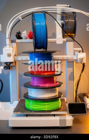 Reihe von farbenfrohen 3D-Druckfilamenten PLA-Material auf umweltfreundlichen und recycelbaren Pappspulen auf schwarzem Kohlefaserhintergrund Stockfoto