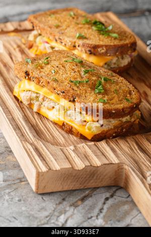Klassisches Thunfischschschmelzsandwich mit Käse auf Butterbrot aus Roggenbrot auf Holzbrett auf dem Tisch. Vertikal Stockfoto
