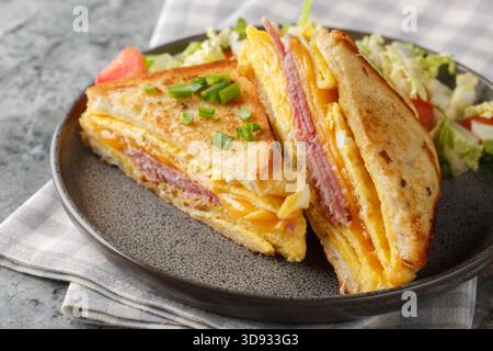 Hausgemachtes Frühstück Ei Sandwich Hack mit Schinken und Käse auf dem Teller auf dem Tisch. Horizontal Stockfoto