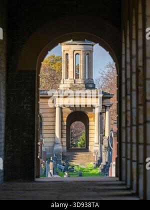 Blick durch einen dunklen Steinbogen zu einem klassischen Turm auf dem Brompton Cemetery, London. Stockfoto