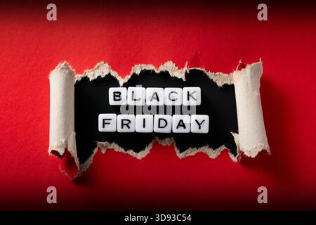 Nahaufnahme des „Black Friday“-Schilds mit Acrylperlen in gerissenem rotem Papier. Hochauflösendes Foto. Stockfoto