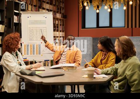 Junger Schwarzer erklärt englische Grammatik in der Bibliothek Stockfoto
