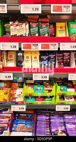 ISERLOHN, DEUTSCHLAND — 27. NOVEMBER 2025: Verschiedene Schokoladentafeln ordentlich im Ladenregal im Lidl-Supermarkt angeordnet Stockfoto