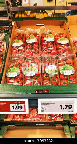 ISERLOHN, DEUTSCHLAND — 27. NOVEMBER 2025: Frische Weintomaten, die heute im Supermarkt Lidl auf einem Regalboden gelagert werden Stockfoto