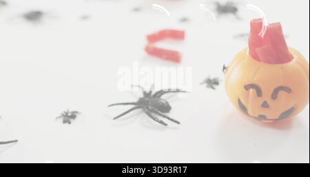 Mit orangefarbenem Jack-o'-Laterne-Container, der auf dem Tisch sitzt, mit schwarzen Spinnen, roten Süßigkeiten, Kopierraum Stockfoto