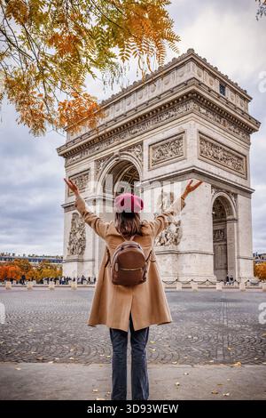 Eine glückliche Touristin auf einem Städtetrip steht vor dem Arc de Triomphe in Paris, Frankreich Stockfoto