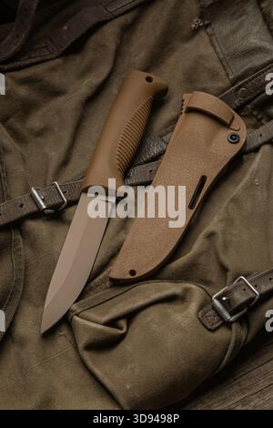 Braunes taktisches Messer mit fester Klinge oder Überlebensmesser mit seiner Ummantelung auf einem Leinentasche. Stockfoto
