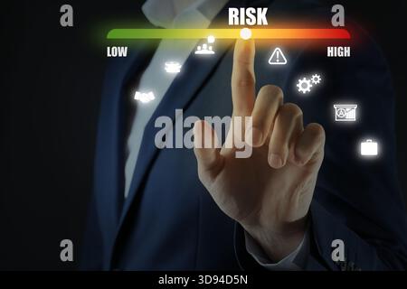 Mann reguliert das Risiko auf virtuellem Bildschirm mit Symbolen vor schwarzem Hintergrund, Nahaufnahme Stockfoto