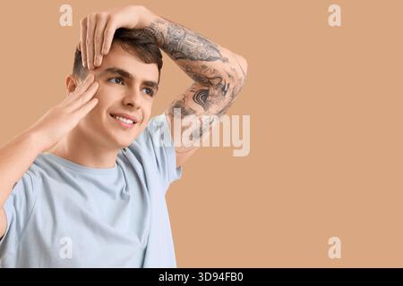 Junger Mann, der Gesichtsaufbauübung auf beigefarbenem Hintergrund macht Stockfoto