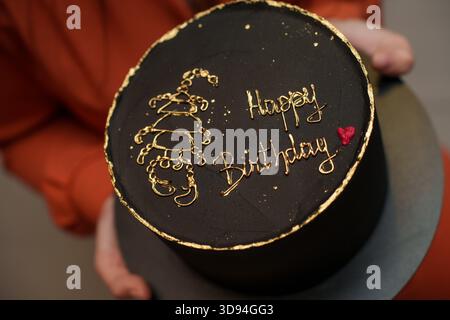 Ein schwarzer Kuchen mit goldenem Skorpion-Design und den Worten Happy Birthday Stockfoto