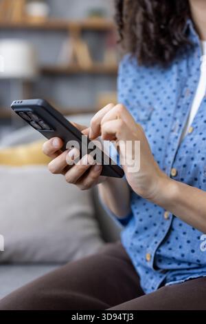 Frauenhände halten ein modernes schwarzes Smartphone, tippen und scrollen auf dem Touchscreen, interagieren mit Mobiltechnologie und digitalen Inhalten Stockfoto
