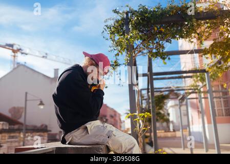Junior Helfer berät Nachbarn über Gartenarbeit auf sonniger Terrasse Stockfoto