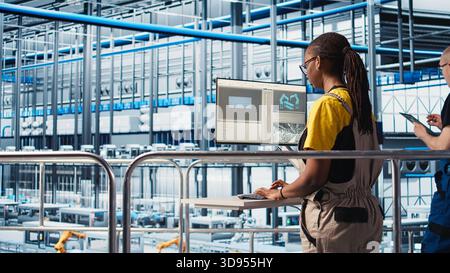 Porträt eines glücklichen Ingenieurs in der intelligenten Photovoltaik-Fabrik, der Daten analysiert und Systemmetriken überprüft. Fröhliche Frau in Industrie 4,0 Solarpaneele Anlage, die erneuerbare Energie produziert, Kamera A Stockfoto
