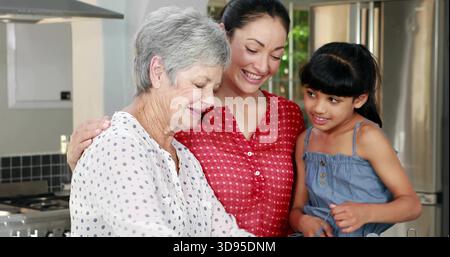 Lächelnde drei Frauen in unterschiedlichen Kleidern, die sich über die Küchentheke mit Gasherd und Backsplash beugen Stockfoto
