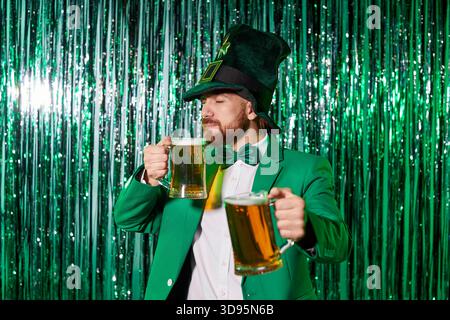 Leprechaun im grünen Anzug, der Bierbecher auf der St. Patricks-Party am Party-Set anklickt Stockfoto