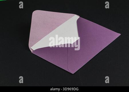 Ein hübsch gefertigter Umschlag verfügt über ein lila Innenfutter vor einem eleganten schwarzen Hintergrund. Das Design unterstreicht eine Kombination aus Farben und Einfachheit. Stockfoto