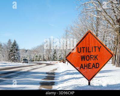 Orangefarbenes SCHILD WARNT DEN Verkehr vor einer Arbeitszone auf einer verschneiten Stadtstraße an einem frostigen und sonnigen Wintertag in Bemidji, Minnesota. Stockfoto