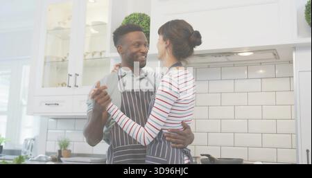 Ein Kochpaar trägt gestreifte Schürzen, macht in der Küche zu Hause Abendessen, Bratpfanne auf dem Herd Stockfoto