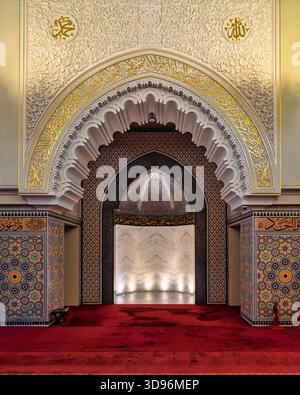 Das Innere der Ash Shaliheen Moschee, Bandar Seri Begawan, Brunei. Reich verzierte Bögen mit goldener arabischer Kalligraphie, komplizierten Schnitzereien und farbenfrohen geometrischen Fliesen, die zum Mihrab führen Stockfoto