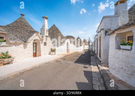 Blick auf eine enge Straße gesäumt von den berühmten Trulli-Häusern in Alberobello, Region Apulien, Italien, UNESCO-Weltkulturerbe. Stockfoto