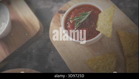 Mit weißer Schüssel mit Tomatensalsa und Rosmarin auf Holzbrett in der Küche, Tortilla Chips Stockfoto